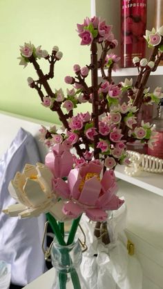 a vase filled with pink flowers sitting on top of a white table next to a book shelf