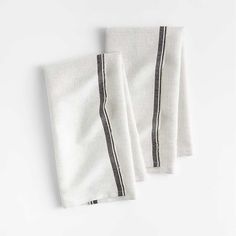 two white napkins with black stripes are on a white tablecloth against a white background