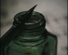 a green glass jar with a pen sticking out of it