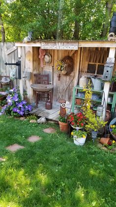 a garden shed with potted plants and flowers on the outside, in front of it