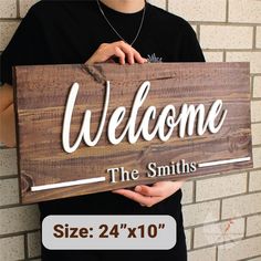 a man holding a wooden sign that says welcome the smiths size 24 x10