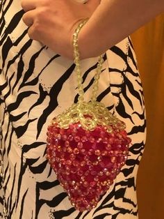 a woman wearing a zebra print shirt holding a red heart shaped beaded purse