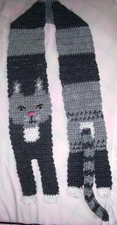 a crocheted scarf with a cat on it and a black striped tie around the neck