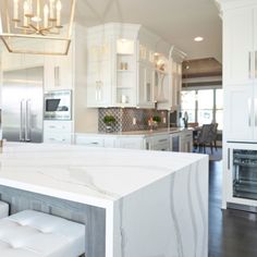 a white kitchen with marble counter tops and stools