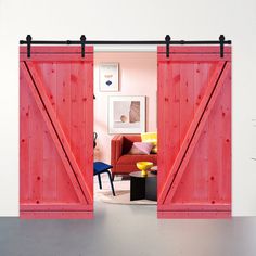 an open red barn door in a living room next to a couch and table with a yellow chair