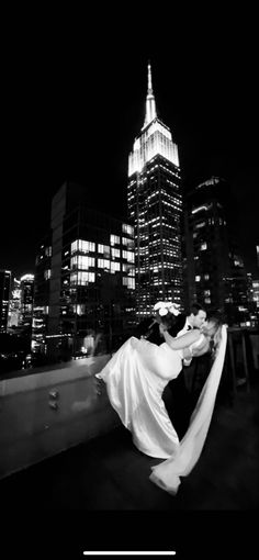 a bride and groom kissing in front of the empire building at night