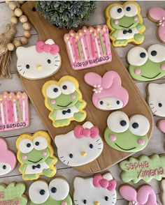 hello kitty birthday cookies are arranged on a wooden board and decorated with pink, green, and yellow icing