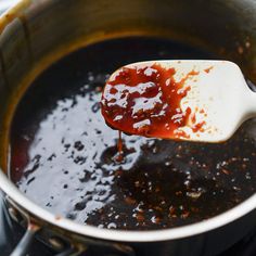 a spoon full of sauce on top of a pot