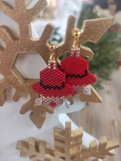 a pair of red and gold beaded earrings on top of a snowflake