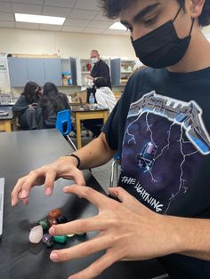 a young man wearing a face mask and holding out his hands to some rocks in front of him