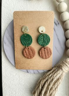 a pair of green and brown earrings sitting on top of a table next to some string