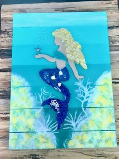 an acrylic painting of a mermaid holding a starfish in her hand on wood planks