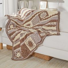 a crocheted blanket is sitting on a couch in front of a bookcase