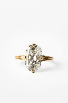 an oval cut diamond ring with two gold bands on the band, set against a white background