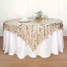 a table topped with a white and gold sequin table cloth