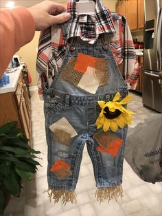 a child's denim overalls with sunflower patchwork on the front and back