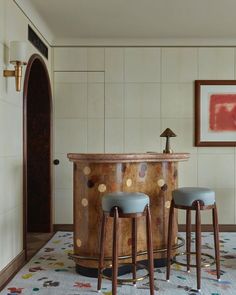 two stools sit in front of a bar with polka dots on the floor and walls