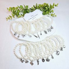 These bracelets are made from acrylic beads coated with an off white pearlescent finish and strung on elastic cording.  The beads are 8mm.  The bracelets circumference is 6.8" to 7.9".  Charms are attached to the bracelets and ready to insert into your already baked and decorated cake.  IN THIS LISTING YOU WILL RECEIVE one of each charm (20 total): BABY CARRIAGE, CAMERA, CHAMPAGNE, CROWN, EIFFEL TOWER, ELEPHANT, FLOWER, FOUR LEAF CLOVER, HEART, HIGH HEEL SHOE, HORSE, LADYBUG, LIGHTHOUSE, MONEY B White Beaded Pearl Charm Bracelet, White Pearl Beaded Charm Bracelet, White Pearl Stretch Bracelet With Pearl Charm, Beaded Pearl Bracelet For Birthday, Adjustable Pearl Beaded Bracelet For Birthday, Adjustable Cream Pearl Bracelet, White Pearl Charm Bracelet, White Pearl Stretch Bracelet For Party, Pearl Beaded Stretch Bracelet For Wedding