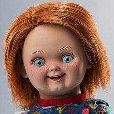 an old doll with red hair and blue eyes is smiling at the camera while wearing a sweater