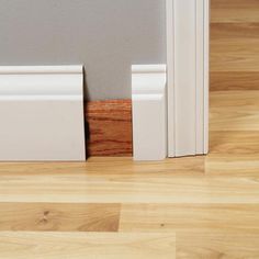 the corner of a room with wood flooring and white trim on the door frame