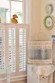 a white birdcage sitting on top of a table next to a window