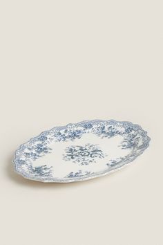 an oval blue and white plate with floral designs on the rim, against a gray background