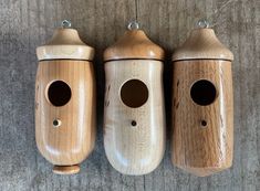 three wooden bird houses are lined up on the wall, with holes in each one