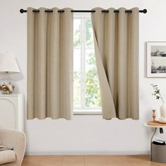 a living room filled with furniture and a window covered in beige drapes next to a chair