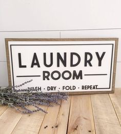 a sign that says laundry room on it next to some lavender sprigs and a plant