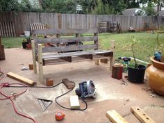 a wooden bench sitting in the middle of a yard next to a garden hoses