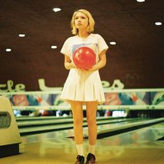 a woman holding a bowling ball in her hands and standing next to a bowling alley