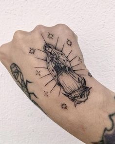 a person with a tattoo on their arm that has a cross in the middle and stars around it