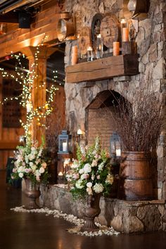 an image of a fireplace with candles and flowers on the mantle in front of it