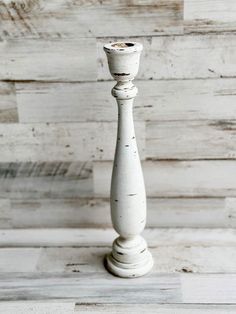 a tall white candle holder sitting on top of a wooden floor