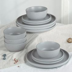 a stack of gray dishes sitting on top of a white table cloth