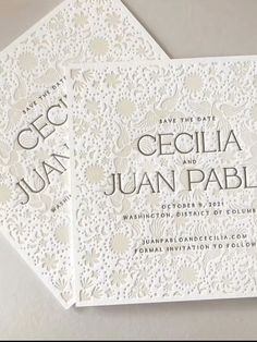 two white wedding cards with laser cut designs on the front and back, sitting next to each other