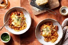 two bowls of spaghetti and bread on a table