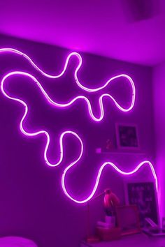 a purple room with neon lights in the shape of a snake on the wall, and a bed next to it