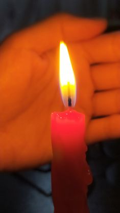 a lit candle in the palm of someone's hand