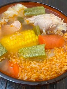 a bowl filled with rice and vegetables on top of a wooden table