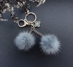 a pair of blue pom - poms hanging from a metal keychain