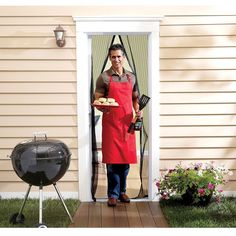 a man in an apron holding a tray of food near a bbq and grill