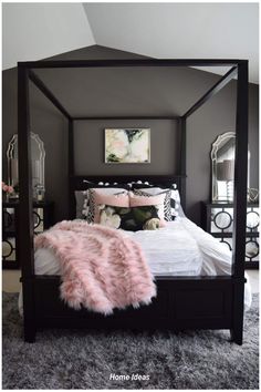 a bedroom with a canopy bed and pink fur rugs on the floor in front of it