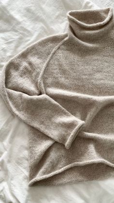 a white sweater laying on top of a bed