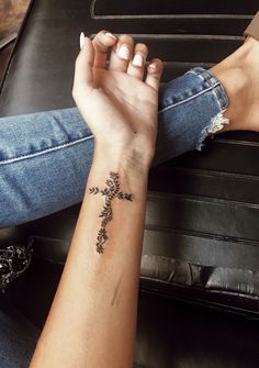 a woman's arm with a cross tattoo on it