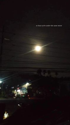 the moon is shining brightly in the dark sky above some power lines and cars at night