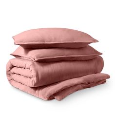 three pillows stacked on top of each other in front of a white background with pink sheets