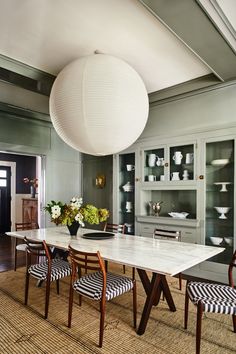 a dining room table with chairs and a large white ball hanging from the ceiling above it