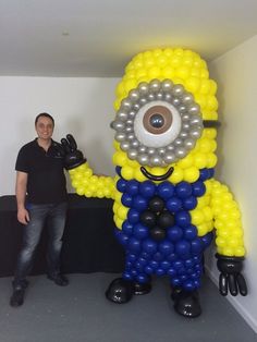 a man standing next to a large balloon sculpture in the shape of a minion