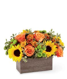 an arrangement of sunflowers and roses in a wooden box on a white background